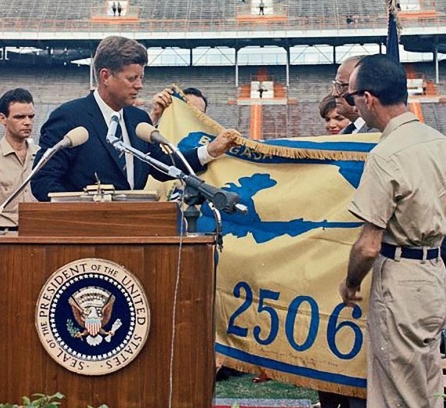 President Kennedy receives the flag of the 2506 Brigade during a ceremony at the Orange Bowl in Miami on December 29, 1962