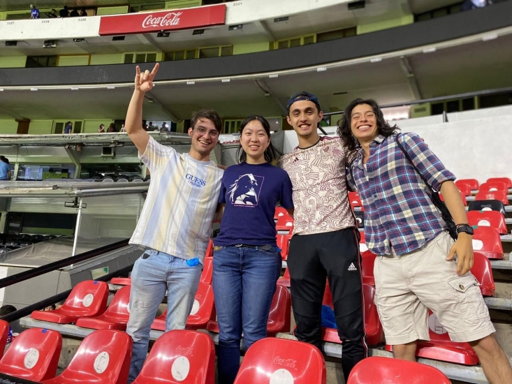 Johan Maysonet Peña with three other MIT students standing in between stadium seats at Estadio Azteca