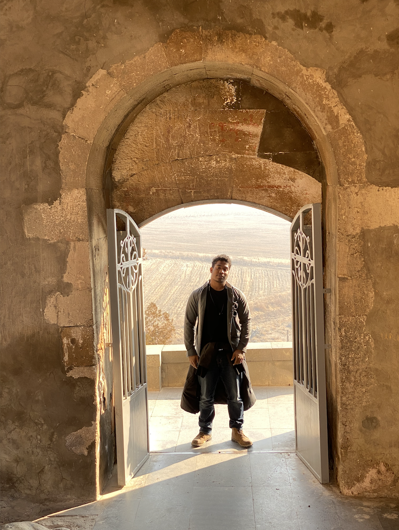 Zachary Francis posing in between a an arched doorway in Khor Virap, Armenia