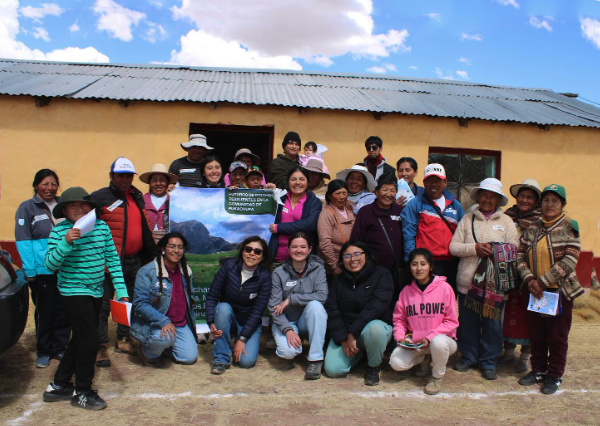 Alison Rufo with locals in Peru in front of a yellow single story house