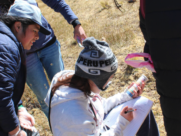 Alison Rufo at work holding a can while writing on paper with someone looking over her shoulder