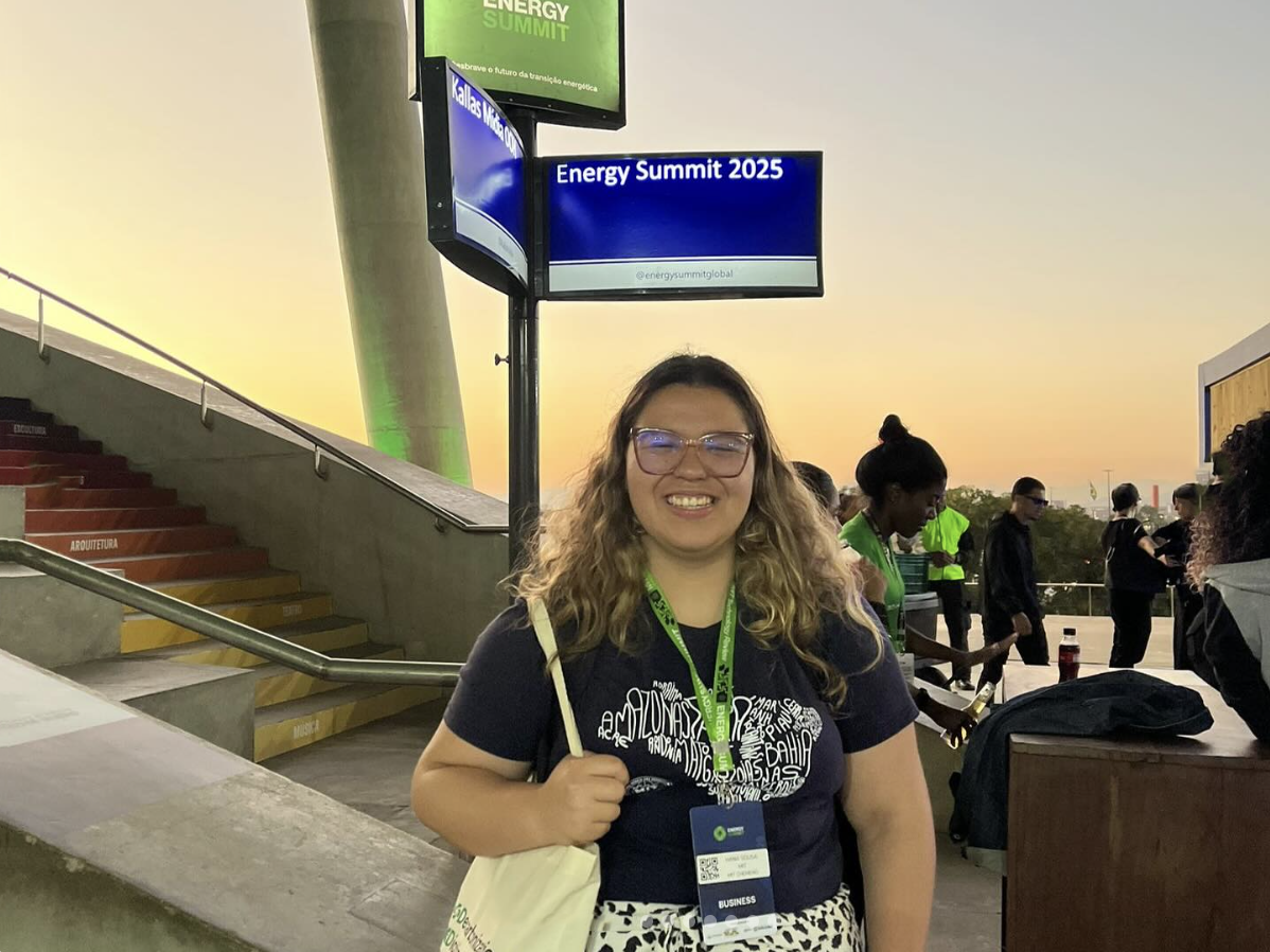 Hana Sousa smiling at the bottom of the staircase with a screen behind her that says "Energy Summit"