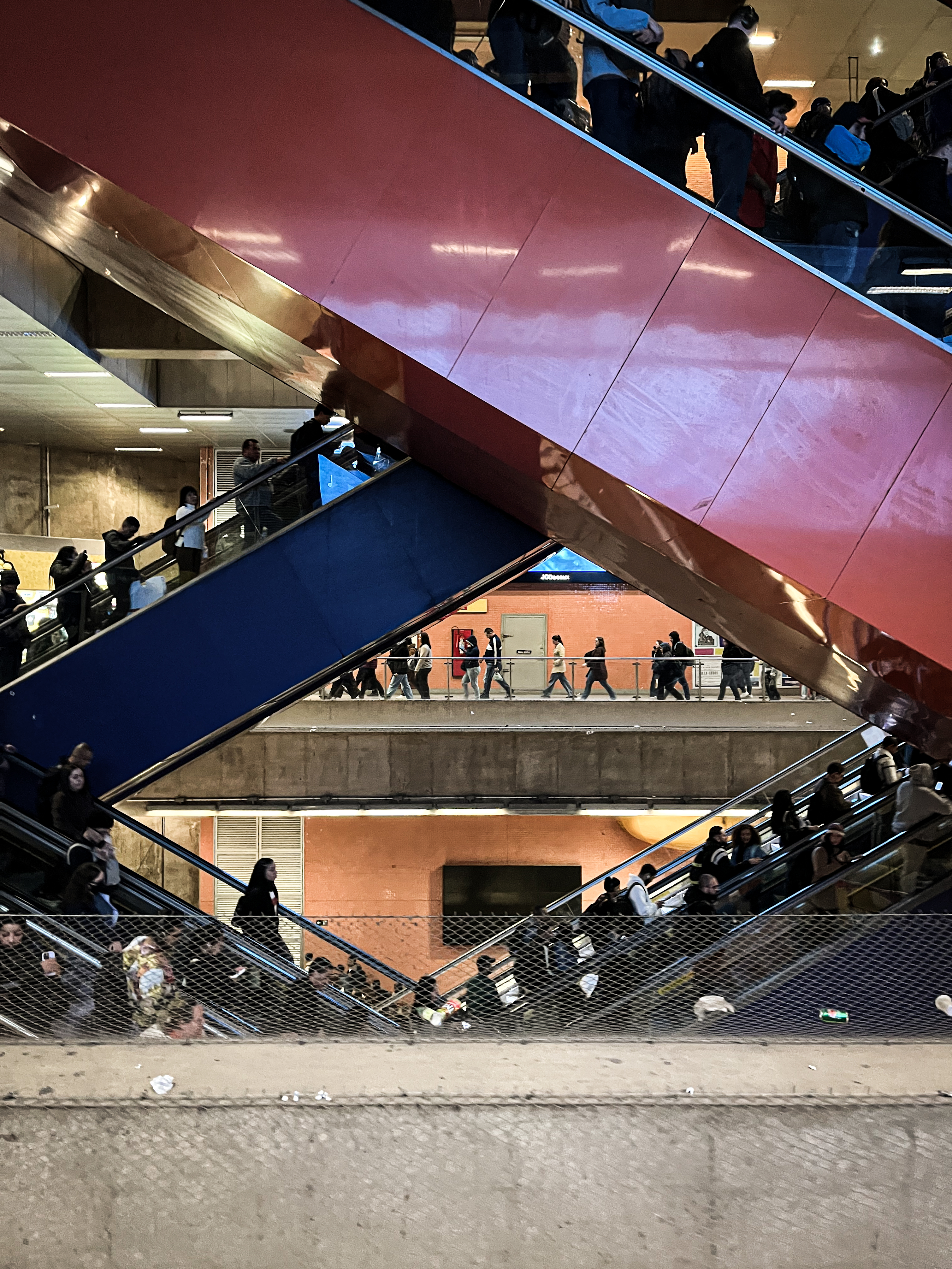 People on escalators going up and down and a picture shows the escalators making a diamond shape