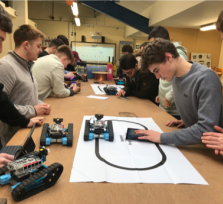 Students working with small robots and laptops