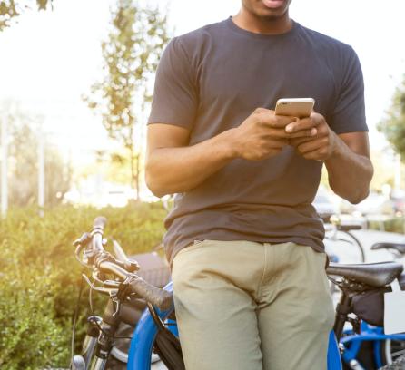 man holding cell phone outdoors next to bikes