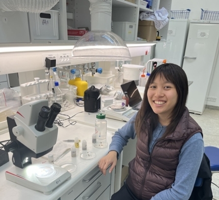 Andrea Lo seated at a lab bench and smiling at the camera
