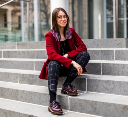 Gazdus sits on the steps of the MIT Media Lab, and her MIT Brass Rat ring is visible.