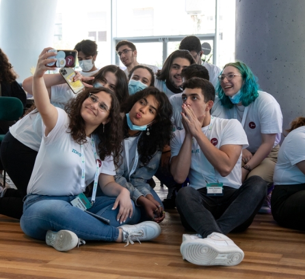 A group of students huddle together taking a selfie photograph