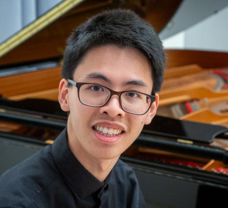 Holden Mui poses for a photo before an open grand piano