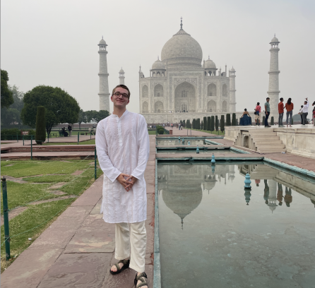 Trevor Kodzis in a white sherwani, an Indian attire, in front of the Taj Mahal
