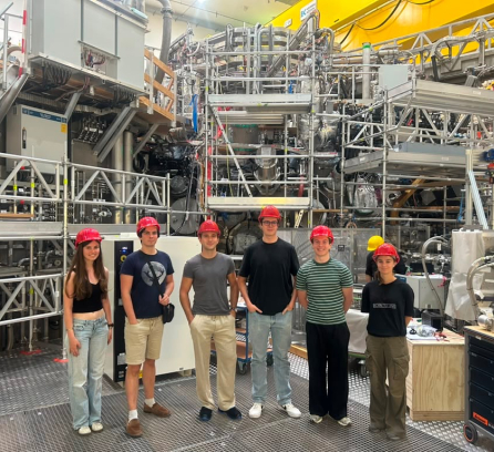 Truman Remenicky and 5 others in red helmets in a work factory filled with steel structures