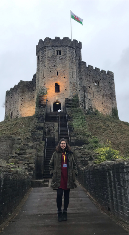 student in front of castle with welsh flag