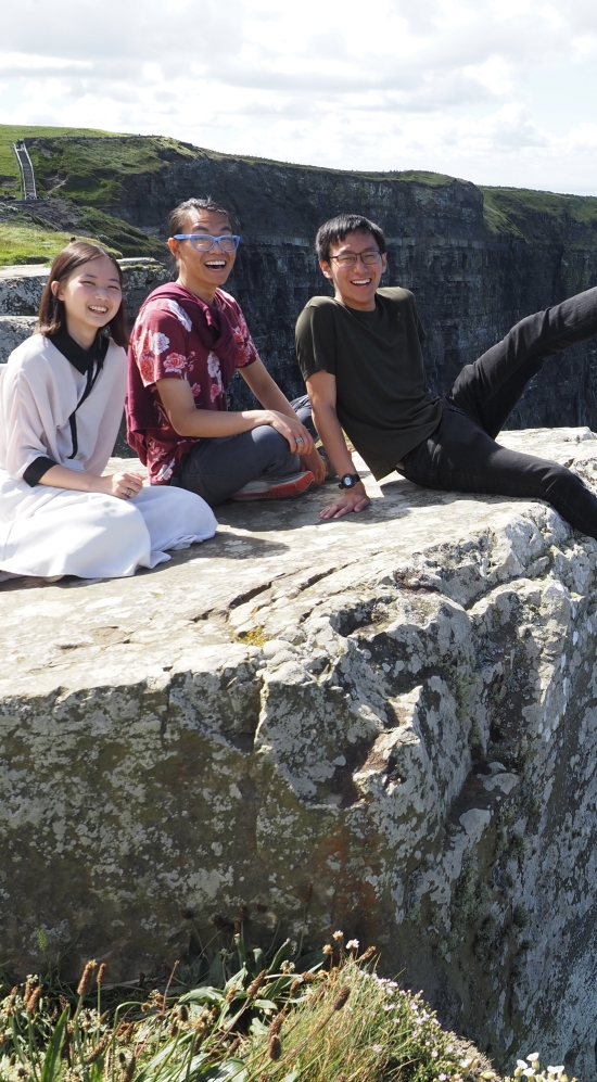 Students sitting on cliff edge by the ocean