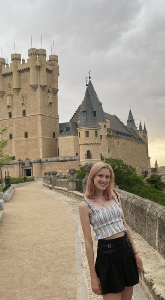 Sierra Green Headshot with the castle in Segovia in Spain in the background during a cloudy day