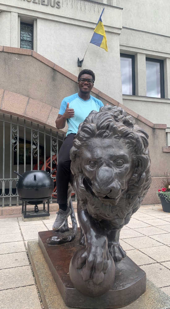 Dami Thomas sitting on a lion statue in Lithuania