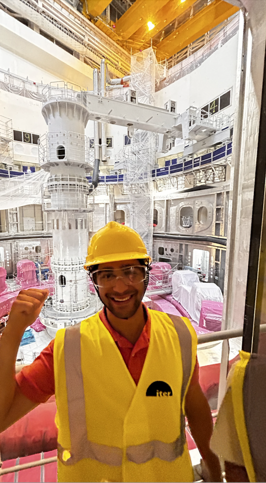 Dilin Meloni dressed in yellow safety vest and cap in front of a glass window into a lab in France