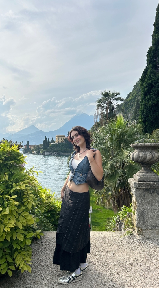 Layla Stanton posing on a bright sunny day with mountain peak silhouettes and green vines running along the steps