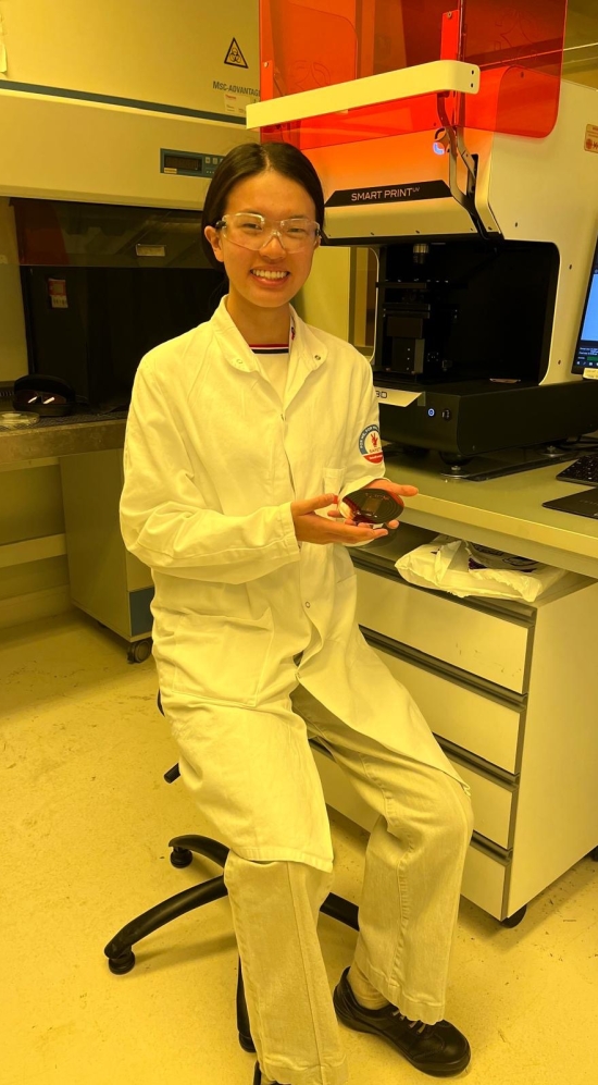 Yijun Yang in a white lab coat and safety glasses in a lab in France