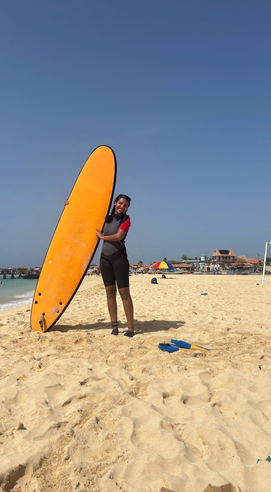 Amulya Aluru on a Cape Verdean beach with a surfboard