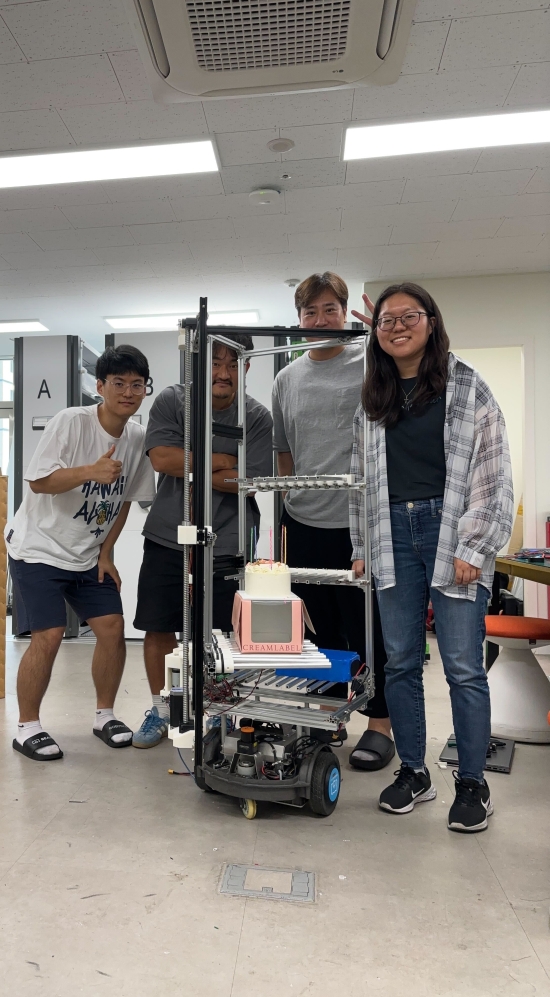 Sarah Park standing next to a robot and three other colleagues