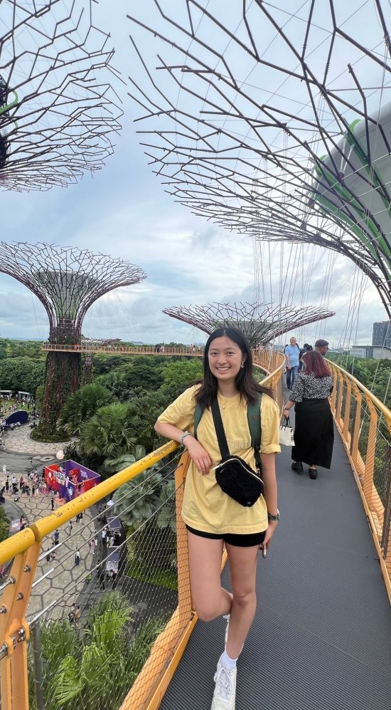 Fiona Shangguan on a bridge, leaning her arm on a yellow railing in Sinagpore