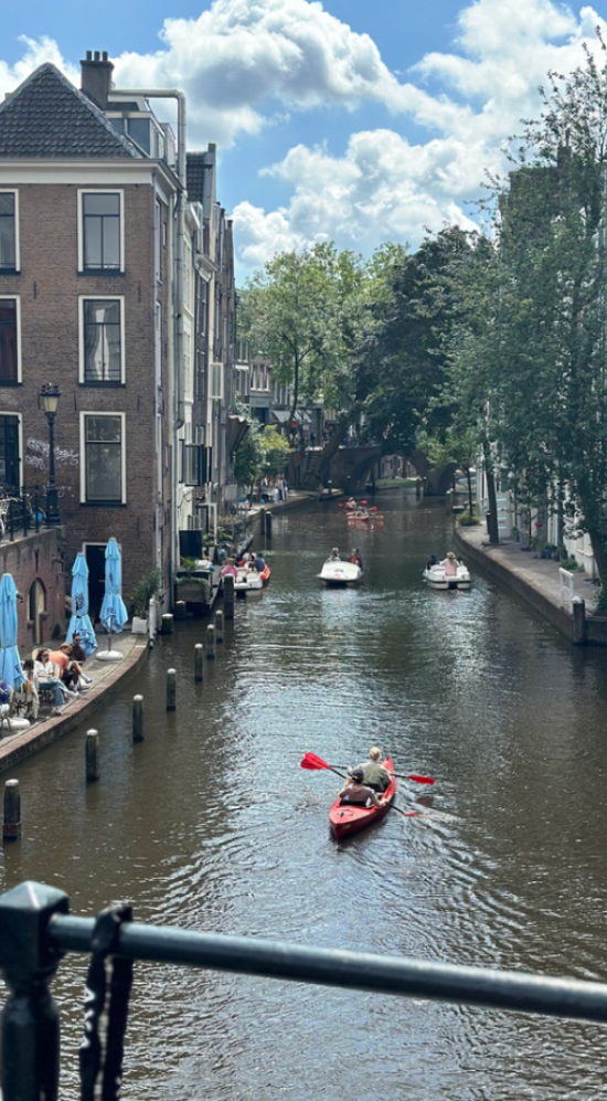 Two people in a red kayak down the Amstel River in Amsterdam on a sunny day with clouds