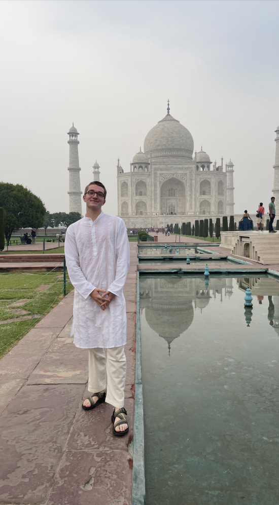 Trevor Kodzis in a white sherwani, an Indian attire, in front of the Taj Mahal