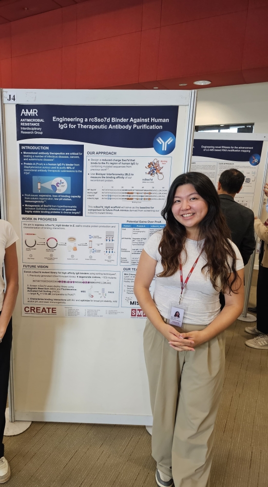 Sidney standing in front of a poster board with hand clasp in the front with someone else to the left