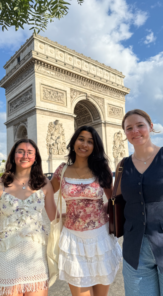Zaee pictured in the middle of two other MISTI students on a sunny day with the Arc de Triomphe in the background
