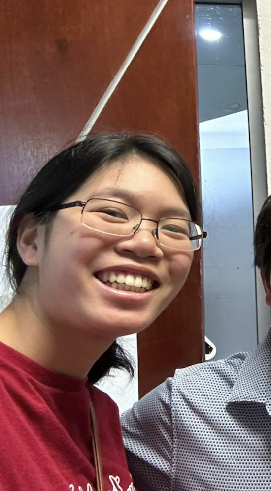 A selfie of Amanda Chung with coworkers with some framed art on the wall of an office