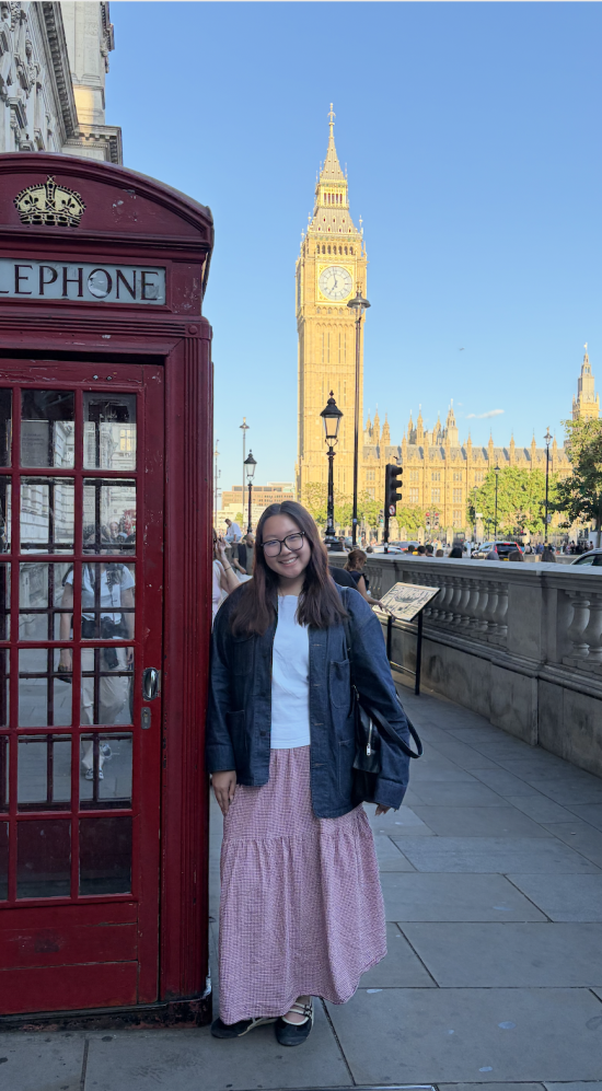 Elaine Chang standing next to a red telephone booth with Big Ben in the background with blue skies