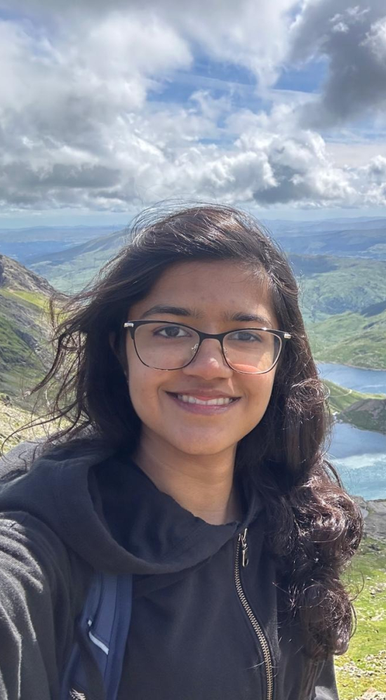 Selfie of Riya S with a mountainous region in the horizon on a cloudy day