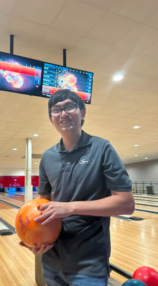 Daniel Alejandro Ochoa Quintero holding an orange bowling bowl at a bpwling alley