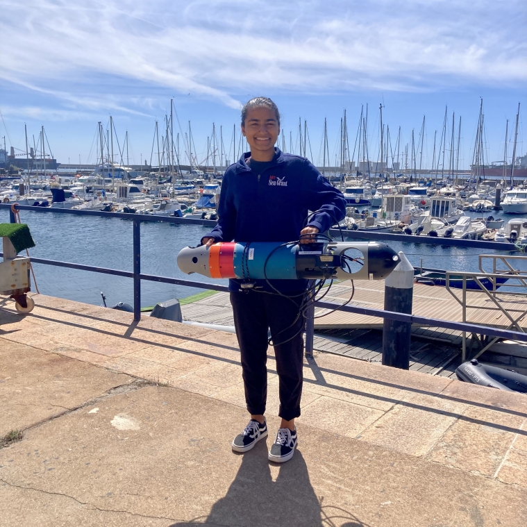 Erin holding a light autonomous underwater vehicle