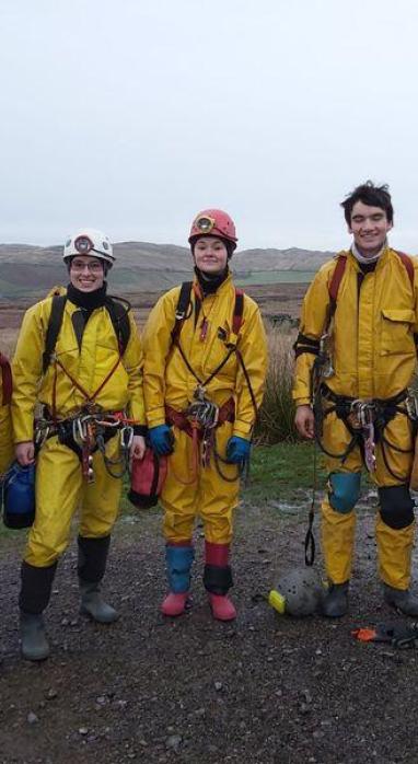 4 people standing in caving gear outdoors