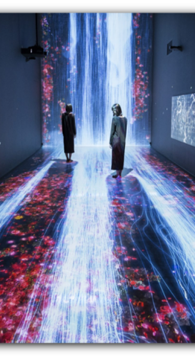 Two people standing in an immersive and colorful gallery with light displays on the floor and walls. This might actually be digital art
