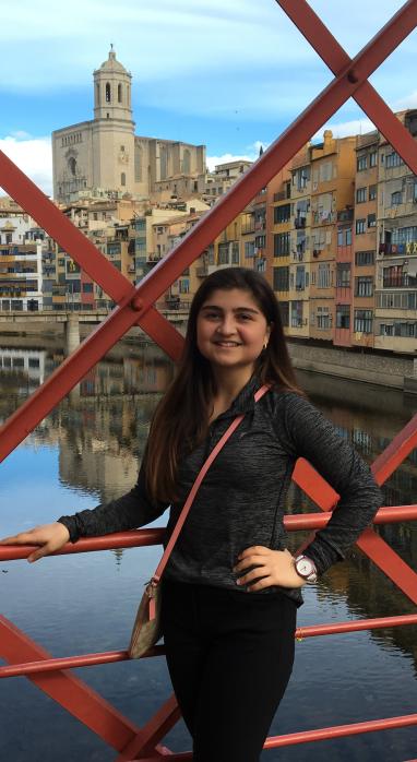 Kimia Ziadkhanpour standing on a bridge with a stream and city in the background
