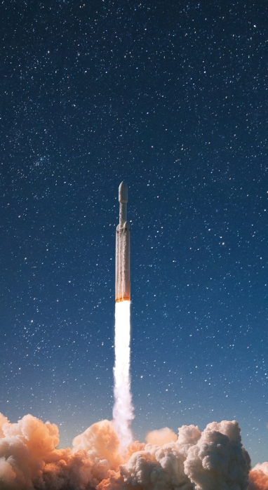 rocket launch into the night sky leaving smoke blast below