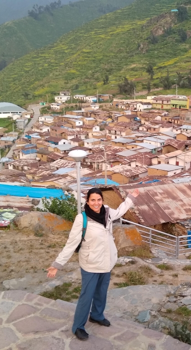 Top shot of Anjuli Jain Figueroa in Peru where there are rolling green hills and colorful maroon roofs of houses in the background