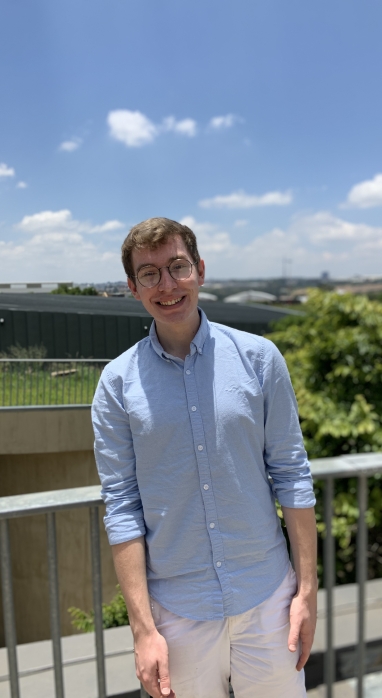 Mid shot of Richard Colwell in front of a fence on the a sunny day with blue skies