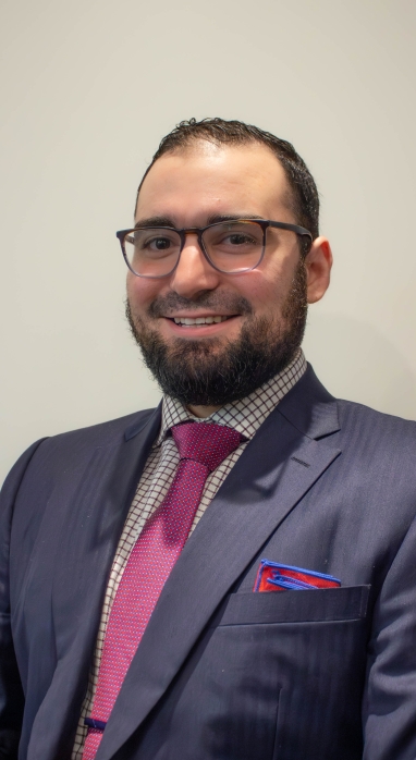 Alberto Hernandez headshot in a suit with pink tie and a red pocket handkerchief 