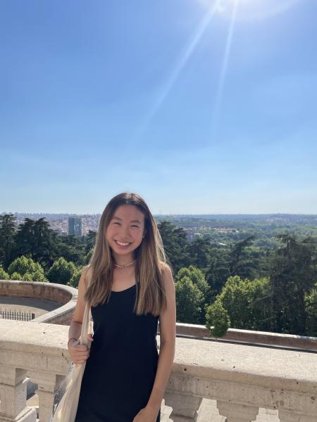 Headshot of Jada Lim in the Royal Palace of Madrid overlooking the Campo del Moro, the 20-acre historic garden and thecity of Madrid, Spain, and a  on a sunny day