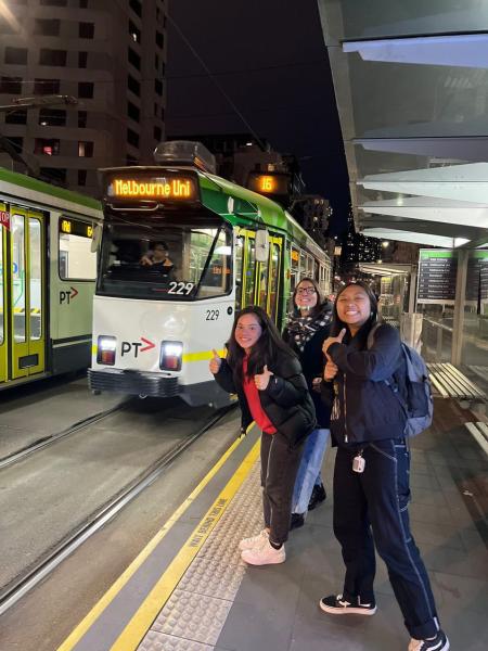 Audrey Chen pictured with two others and Melbourne's green trams on the platform