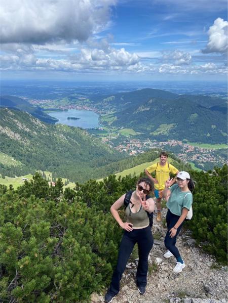 Willow Huang pictured with two others on a hike with a green mountainous region with a lake in the distance