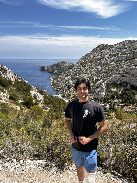 Dilin Meloni on a hike with the sea and rocky plains in the background on a sunny day with clear blue skies and clouds