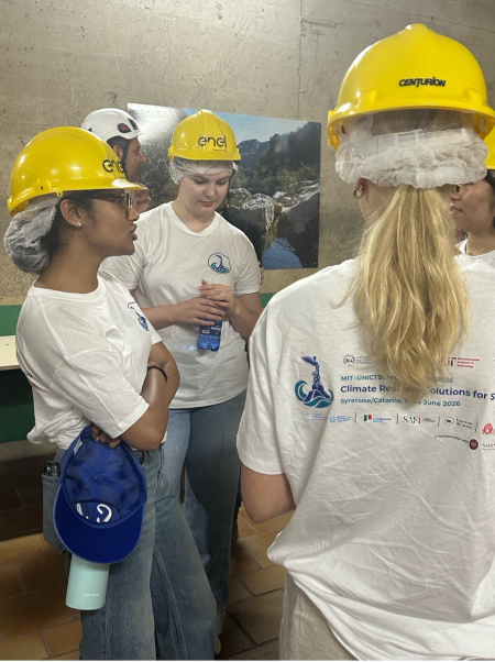MIT students in yellow helmets huddled around discussing something