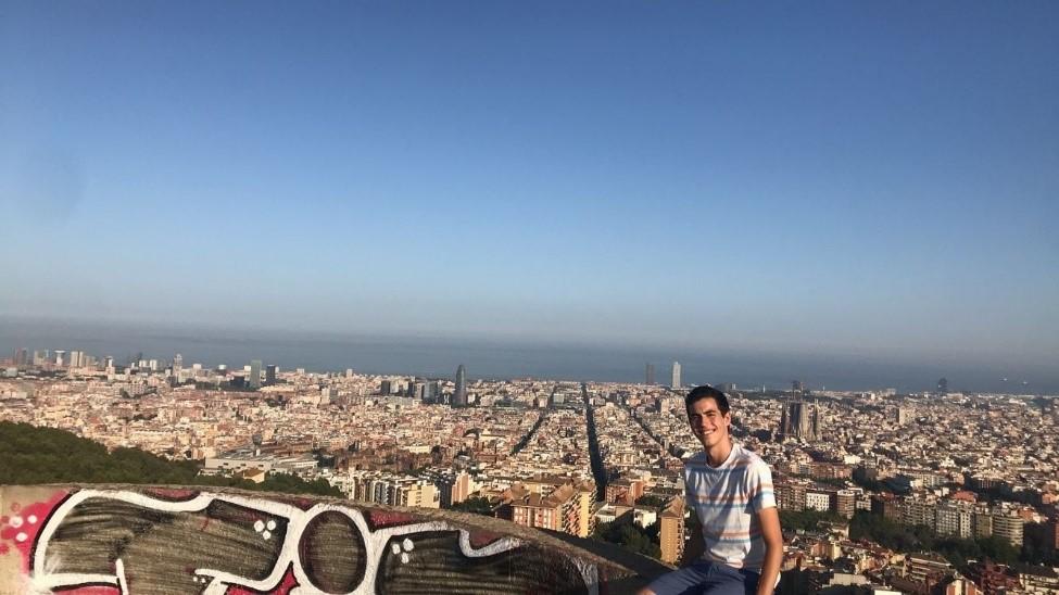 Roland sitting on a wall with Barcelona behind him 