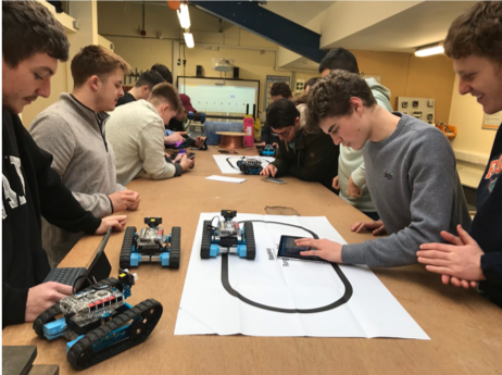 Students working with small robots and laptops