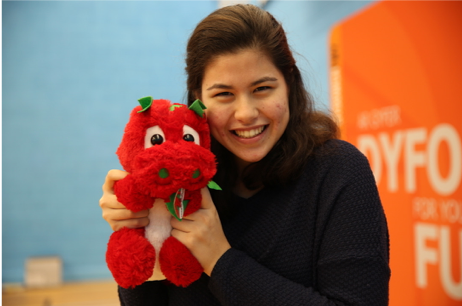 Student smiles with cuddly toy dragon