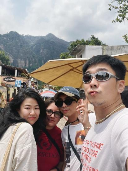 A selfie of Daisy Zhang and 3 other friends in the town of Tepoztlán in Mexico with a row of shop lots and colorful, large umbrellas